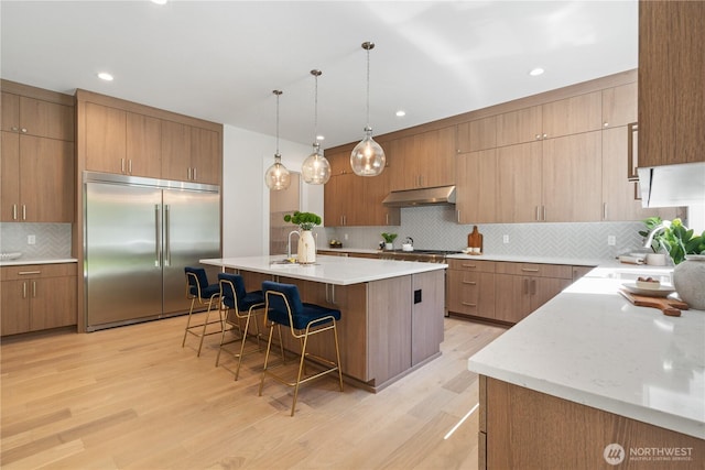 14511 SE 21st Pl, Bellevue, WA 98007 - kitchen featuring stainless steel appliances, under cabinet range hood, a sink, backsplash, and a kitchen breakfast bar
