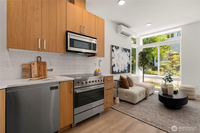 3609 Linden Ave N, Seattle, WA 98103 - kitchen with appliances with stainless steel finishes, a wall mounted air conditioner, light wood-style floors, decorative backsplash, and recessed lighting