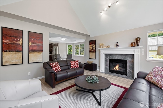 6579 Gleneagle Ave SW, Port Orchard, WA 98367 - living area with light wood-type flooring, healthy amount of natural light, vaulted ceiling, a fireplace, and baseboards