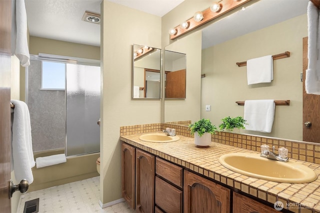 4906 157th Ave SE, Bellevue, WA 98006 - bathroom with double vanity, tile patterned floors, combined bath / shower with glass door, toilet, and decorative backsplash