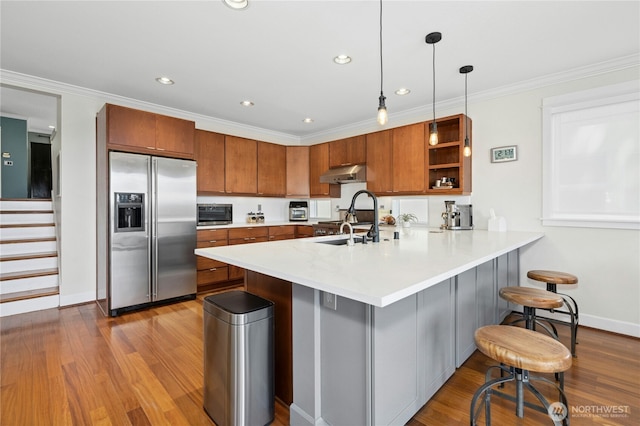 1109 30th Ave S, Seattle, WA 98144 - kitchen with stainless steel fridge, under cabinet range hood, a sink, brown cabinetry, and a peninsula