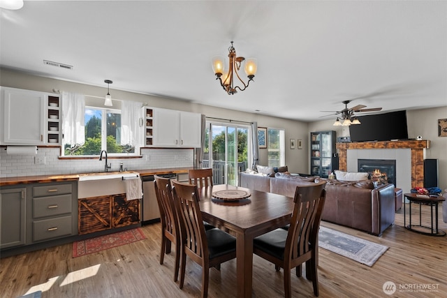 10096 Terra Glenn St SE, Yelm, WA 98597 - dining room featuring light wood-type flooring, a glass covered fireplace, a chandelier, and a ceiling fan