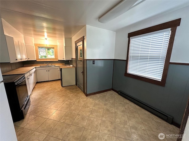 381 Trillium Ave, Forks, WA 98331 - kitchen featuring a baseboard heating unit, black range with electric cooktop, white cabinetry, light tile patterned flooring, and wainscoting