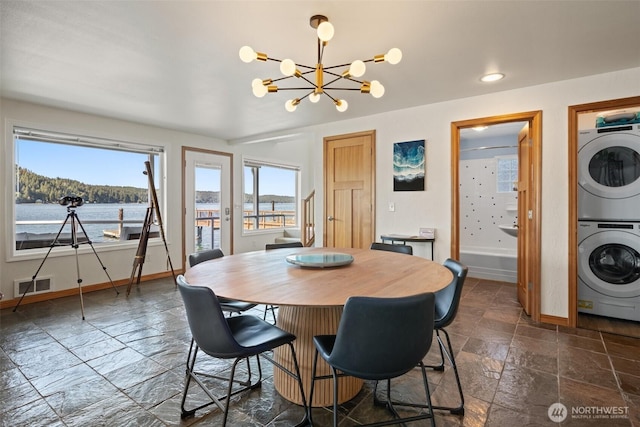 9451 E State Route 106, Union, WA 98592 - dining room featuring stacked washer / drying machine, baseboards, stone tile floors, and a chandelier