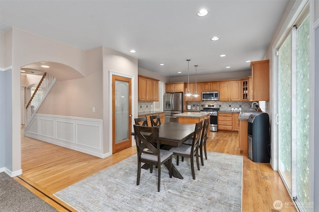 13327 SE 279th Pl, Kent, WA 98042 - dining space featuring light wood-style floors, arched walkways, wainscoting, recessed lighting, and stairs