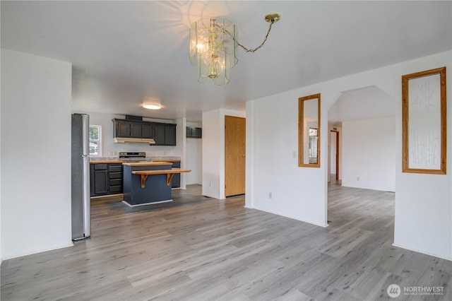866 112th St S, Parkland, WA 98444 - kitchen with appliances with stainless steel finishes, a chandelier, under cabinet range hood, wood finished floors, and open floor plan