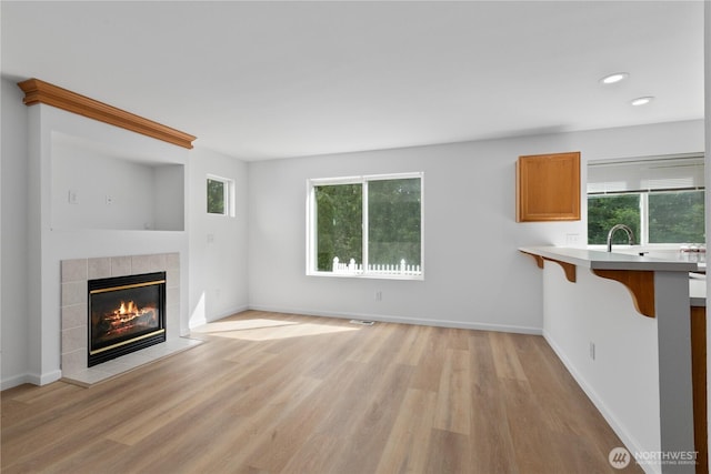 4817 SE 147th Pl, Everett, WA 98208 - unfurnished living room with a tile fireplace, light wood-style floors, plenty of natural light, recessed lighting, and baseboards