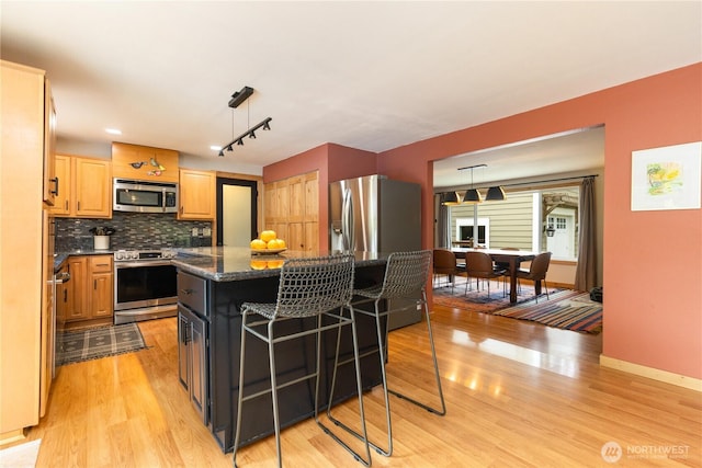 26933 NE Cherry St, Duvall, WA 98019 - kitchen with appliances with stainless steel finishes, light wood-type flooring, decorative backsplash, a kitchen island, and a kitchen breakfast bar
