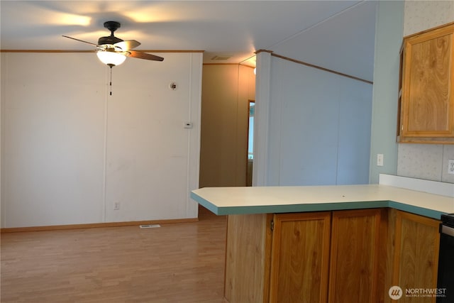 10711 62nd St E Unit 81A, Puyallup, WA 98372 - kitchen featuring light wood-type flooring, a ceiling fan, light countertops, brown cabinets, and ornamental molding