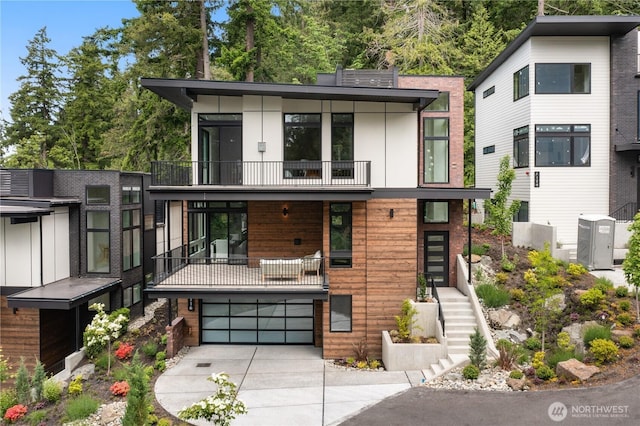 7116 NE 119th Ln, Kirkland, WA 98034 - contemporary house featuring a balcony, stairs, concrete driveway, and a garage