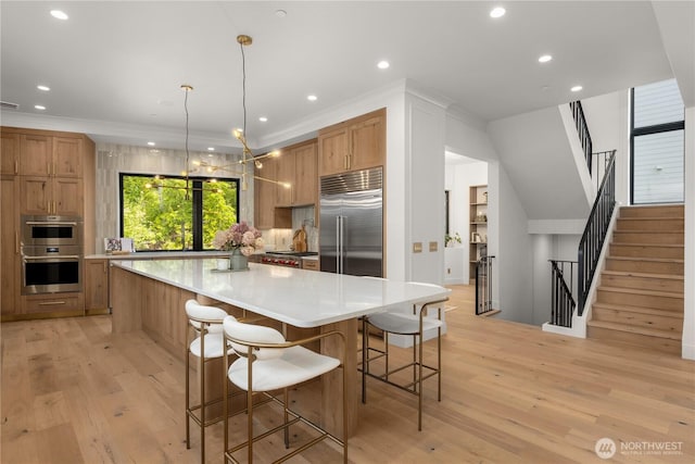 7116 NE 119th Ln, Kirkland, WA 98034 - kitchen with stainless steel appliances, light wood-type flooring, a spacious island, light countertops, and a breakfast bar area