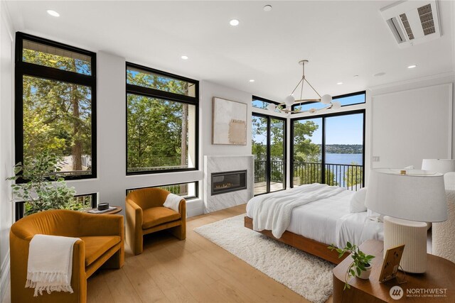 7116 NE 119th Ln, Kirkland, WA 98034 - bedroom with access to outside, a water view, light wood-style flooring, a wall of windows, and a premium fireplace