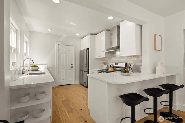 2614 E Olive St, Seattle, WA 98122 - kitchen featuring appliances with stainless steel finishes, wall chimney exhaust hood, a sink, open shelves, and a peninsula
