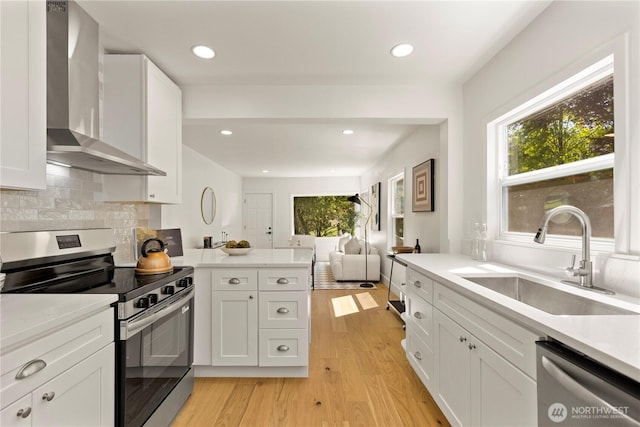 2614 E Olive St, Seattle, WA 98122 - kitchen featuring appliances with stainless steel finishes, wall chimney range hood, a sink, open floor plan, and light wood finished floors