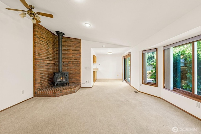 6410 151st Ave E, Sumner, WA 98390 - unfurnished living room featuring a wood stove, vaulted ceiling, carpet, and baseboards