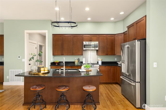 3029 Yankee Girl Cir NE, Bainbridge Island, WA 98110 - kitchen featuring stainless steel appliances, a sink, light wood-style floors, a kitchen breakfast bar, and a kitchen island with sink