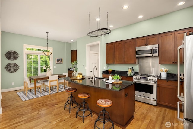 3029 Yankee Girl Cir NE, Bainbridge Island, WA 98110 - kitchen featuring appliances with stainless steel finishes, a sink, light wood-style flooring, a kitchen breakfast bar, and a center island with sink