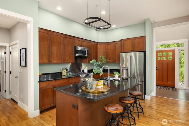 3029 Yankee Girl Cir NE, Bainbridge Island, WA 98110 - kitchen with stainless steel appliances, light wood finished floors, dark stone counters, a kitchen breakfast bar, and recessed lighting