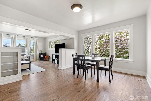 1102 Tecumseh St, Aberdeen, WA 98520 - dining space featuring wood finished floors, an AC wall unit, baseboards, and a wood stove