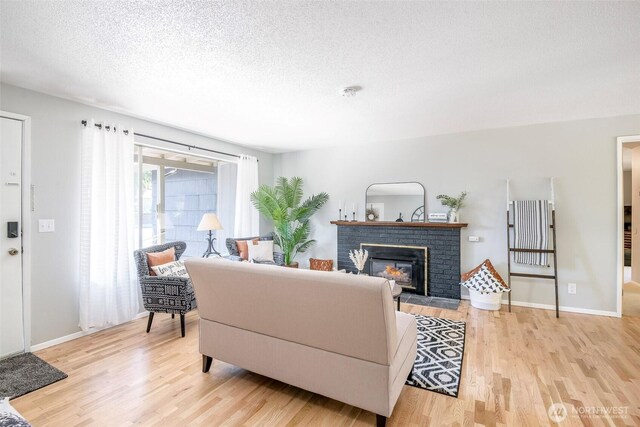 5907 N 31st St, Tacoma, WA 98407 - living room featuring light wood-style floors, a fireplace, a textured ceiling, and baseboards
