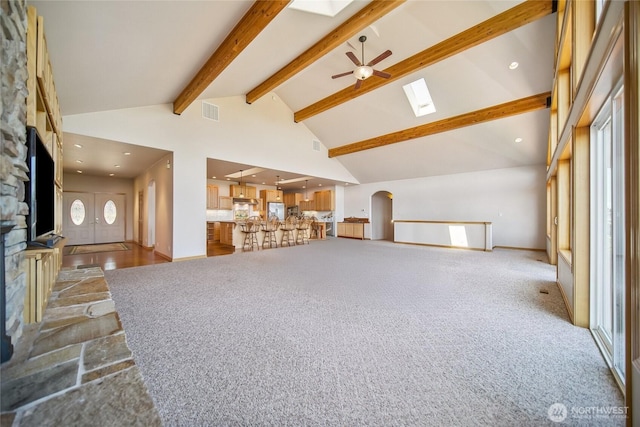 8151 E Seaview Dr, Port Orchard, WA 98366 - unfurnished living room featuring a skylight, a fireplace, beam ceiling, carpet floors, and a ceiling fan