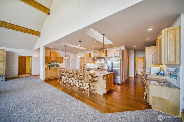 8151 E Seaview Dr, Port Orchard, WA 98366 - kitchen featuring stainless steel fridge, under cabinet range hood, light brown cabinets, a breakfast bar area, and beam ceiling