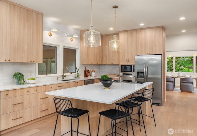 12909 Spanaway Loop Rd S, Tacoma, WA 98444 - kitchen featuring light brown cabinetry, stainless steel appliances, a sink, a kitchen breakfast bar, and recessed lighting