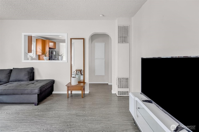 411 7th St SE, Auburn, WA 98002 - living area featuring a heating unit, dark wood finished floors, a textured ceiling, arched walkways, and baseboards