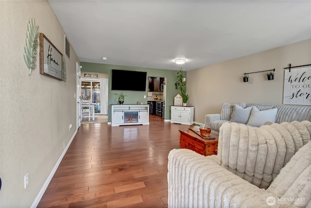 20003 13th Avenue Ct E, Spanaway, WA 98387 - living room with a warm lit fireplace, baseboards, wood finished floors, and a textured wall