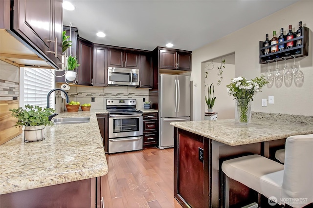 20003 13th Avenue Ct E, Spanaway, WA 98387 - kitchen featuring stainless steel appliances, a sink, light wood-style floors, a breakfast bar, and a peninsula