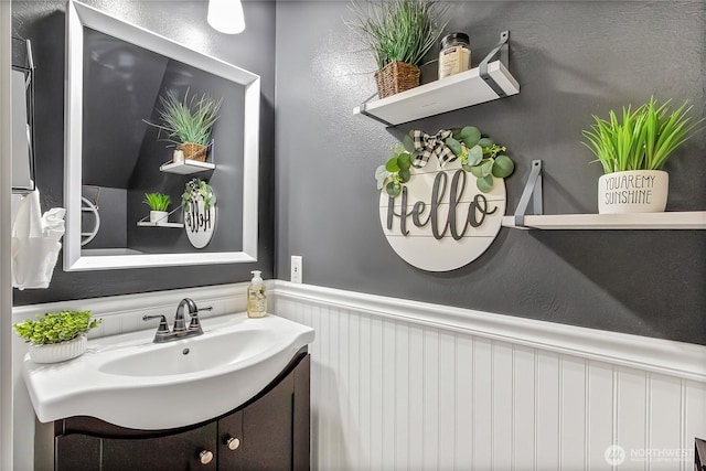20003 13th Avenue Ct E, Spanaway, WA 98387 - bathroom featuring wainscoting, vanity, and a decorative wall