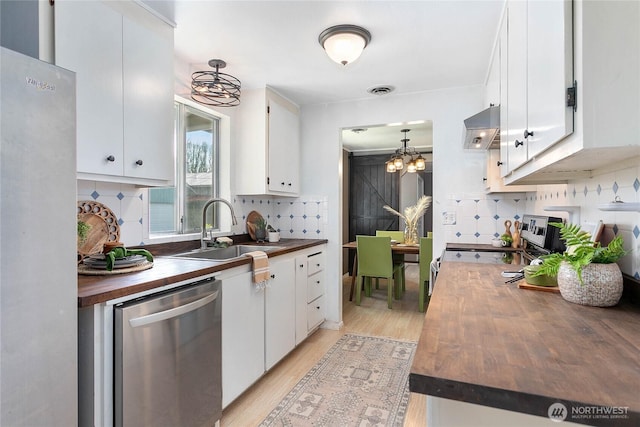 1669 Grandview Pl, Ferndale, WA 98248 - kitchen with butcher block countertops, stainless steel appliances, a sink, a chandelier, and ventilation hood