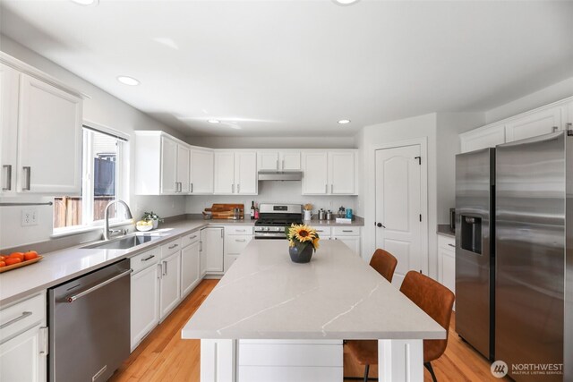 11724 1st Pl SE, Lake Stevens, WA 98258 - kitchen with appliances with stainless steel finishes, under cabinet range hood, a sink, a breakfast bar area, and white cabinets