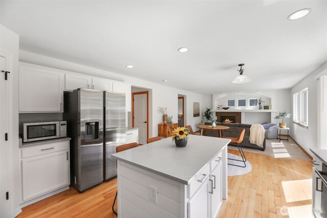 11724 1st Pl SE, Lake Stevens, WA 98258 - kitchen with appliances with stainless steel finishes, a center island, a warm lit fireplace, light wood-style floors, and recessed lighting