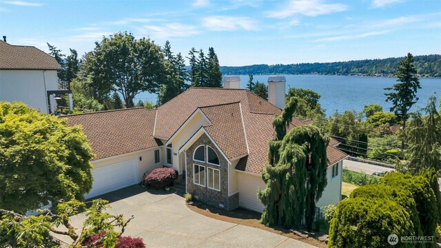 1653 204th Ave NE, Sammamish, WA 98074 - view of front facade with stone siding, driveway, an attached garage, a chimney, and a water view