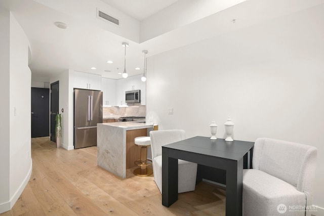10650 NE 9th Pl Unit 3210, Bellevue, WA 98004 - kitchen featuring stainless steel appliances, light wood-style floors, white cabinetry, decorative backsplash, and light countertops