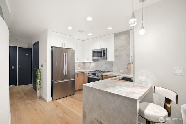10650 NE 9th Pl Unit 3210, Bellevue, WA 98004 - kitchen with appliances with stainless steel finishes, a peninsula, a sink, light countertops, and light wood finished floors