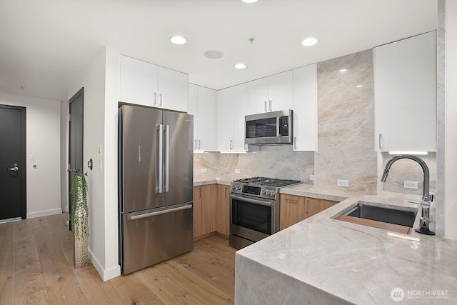 10650 NE 9th Pl Unit 3210, Bellevue, WA 98004 - kitchen featuring appliances with stainless steel finishes, a sink, light wood-style floors, decorative backsplash, and white cabinets