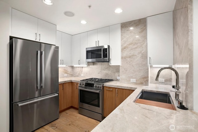 10650 NE 9th Pl Unit 3210, Bellevue, WA 98004 - kitchen featuring stainless steel appliances, a sink, light wood finished floors, backsplash, and white cabinets