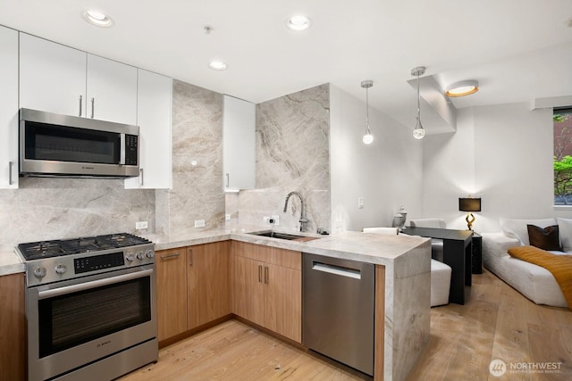 10650 NE 9th Pl Unit 3210, Bellevue, WA 98004 - kitchen with stainless steel appliances, a sink, open floor plan, light wood-style floors, and a peninsula