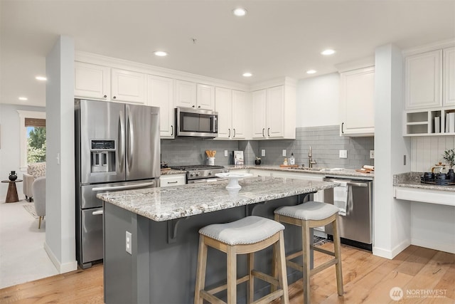 35314 SE Sequoia Pl Unit B, Snoqualmie, WA 98065 - kitchen featuring appliances with stainless steel finishes, white cabinets, a sink, a center island, and decorative backsplash