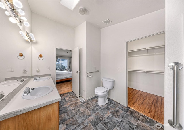 6350 Portal Way Unit 75, Ferndale, WA 98248 - full bathroom featuring double vanity, stone finish floors, toilet, a walk in closet, and baseboards