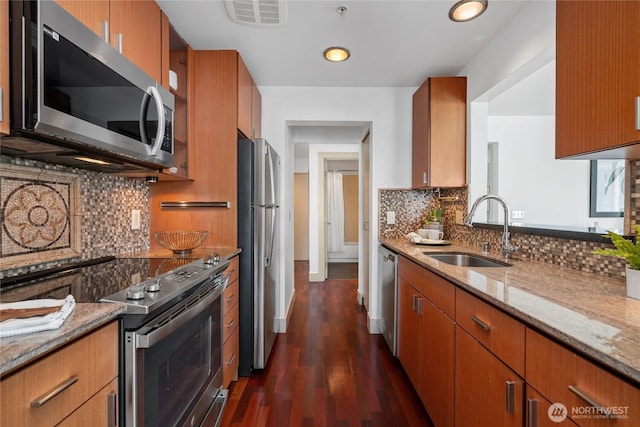 1711 E Olive Way Unit 519, Seattle, WA 98102 - kitchen featuring stainless steel appliances, a sink, brown cabinetry, light stone countertops, and recessed lighting