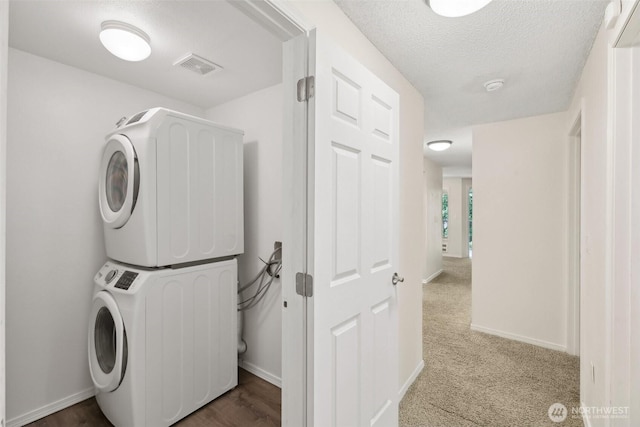 12515 NE 116th St Unit B23, Kirkland, WA 98034 - laundry room with estacked washer and dryer, baseboards, a textured ceiling, and carpet floors