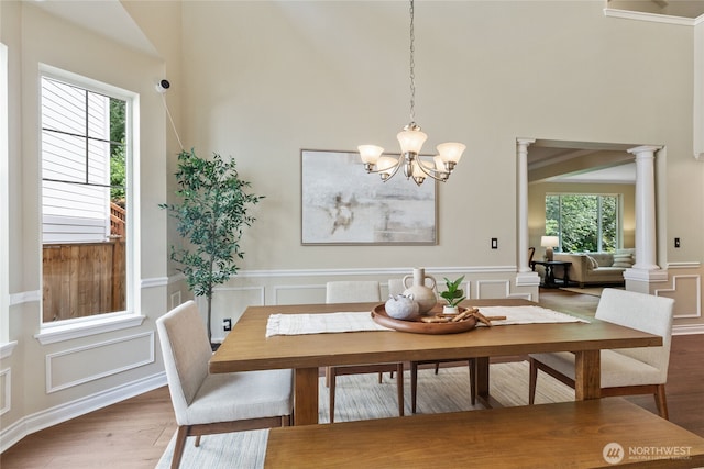 111 170th St SE, Bothell, WA 98012 - dining space with wood finished floors, a decorative wall, a chandelier, ornate columns, and a towering ceiling