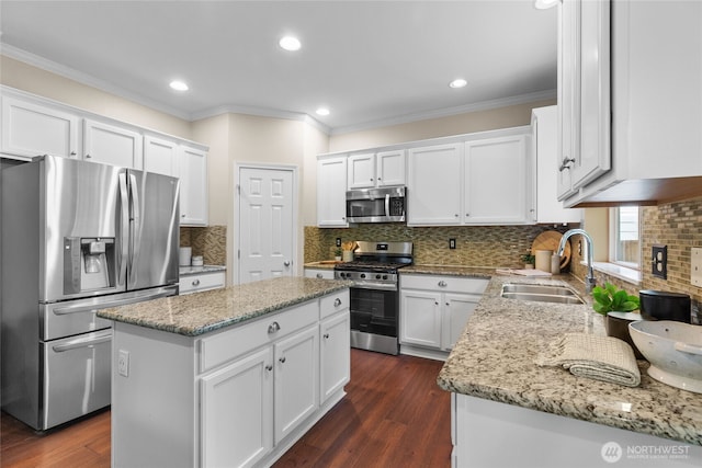 111 170th St SE, Bothell, WA 98012 - kitchen featuring appliances with stainless steel finishes, a kitchen island, white cabinetry, crown molding, and light stone countertops