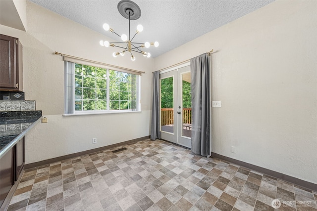 11401 69th Pl S, Seattle, WA 98178 - unfurnished dining area with a chandelier, baseboards, french doors, a textured ceiling, and stone finish flooring