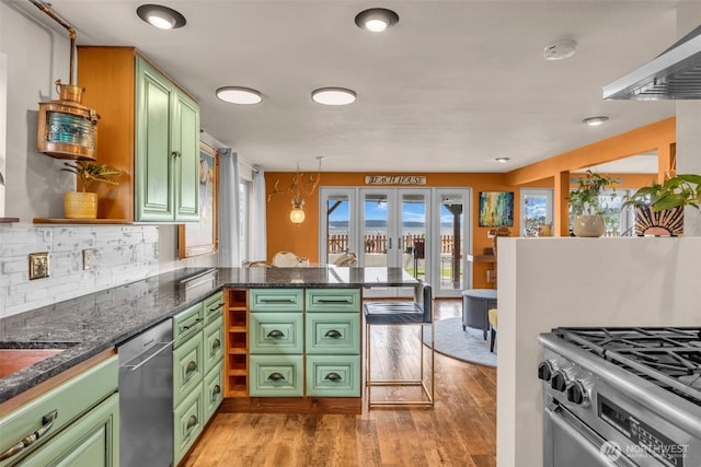 1811 Bay St, Port Orchard, WA 98366 - kitchen featuring green cabinets, stainless steel appliances, a peninsula, light wood-style flooring, and tasteful backsplash