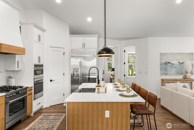 1516 131st Ave NE, Lake Stevens, WA 98258 - kitchen featuring appliances with stainless steel finishes, custom exhaust hood, a sink, a kitchen breakfast bar, and dark wood-style flooring