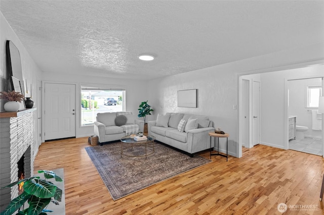 659 NW New York Ave, Chehalis, WA 98532 - living room featuring wood finished floors, a textured ceiling, a fireplace, and baseboards
